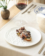Bruschetta with roast beef and greens on white plate with wine