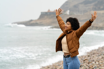 Young woman enjoying freedom on the beach with open arms