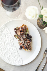 Bruschetta with roast beef and greens on white plate with wine
