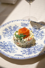 Portion of gourmet olivier salad with salmon on white background