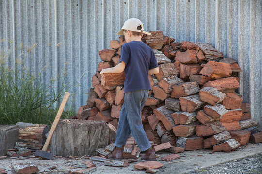 Young boy carrying wood to chop