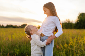 Two joyous young girls, one embracing the other, share a moment of laughter and connection in a...