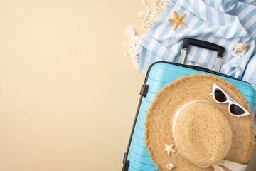 Top view of a vacation setup featuring blue suitcase, straw hat, and holiday items