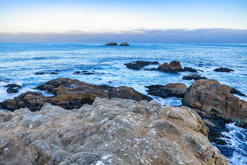 Scenic coastal view at Garrapata State Park near Big Sur, California, showcasing rugged cliffs, vibrant plants, and the Pacific Ocean along the iconic Highway 1 on a clear spring day