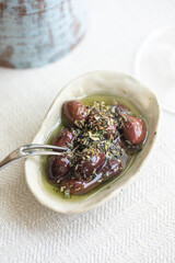 Marinated kalamata olives with herbs and olive oil in ceramic bowl