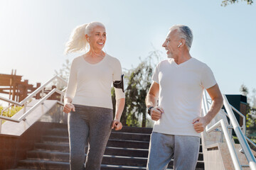 Senior couple runners training outdoors, running jogging outside in city center, happy retired...