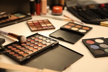 Different makeup products and brushes on dressing table indoors, closeup