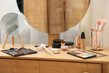 Different makeup products and brushes on vanity indoors, closeup