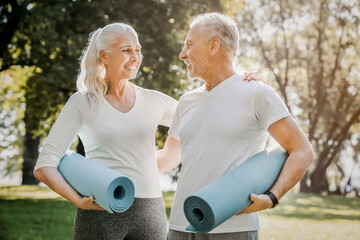 Active sporty healthy smiling elderly couple family going to workout outdoors in park holding mats...