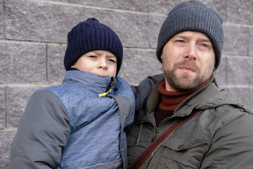 Father and son walking down on sidewalk together. Portrait of a handsome middle-aged man with...