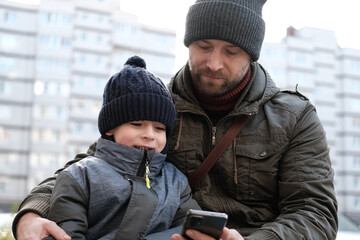 Father and son walking down on sidewalk together. Portrait of a handsome middle-aged man with...