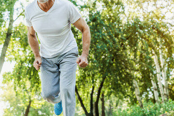 Cropped shot of senior athletic man, runner in sportswear, stands at the starting position on the...