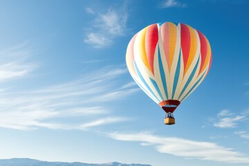 Obraz premium Soaring High: A vibrant hot air balloon floats gracefully against a stunning blue sky, creating a captivating scene of adventure and freedom. 