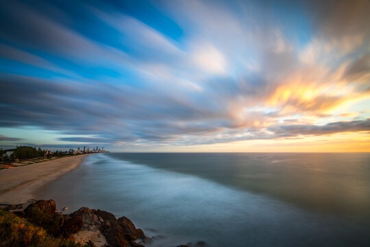 Long exposure view over beach and ocean with streaky clouds