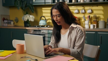 Tired stressed Latino American woman businesswoman working computer at home kitchen distant...