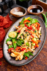 Asian food stir fried green peas with chicken and vegetables, sesame seeds vertical photo