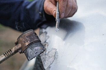 Car body shop. Repair man processes the welding seam using an angle grinder on replaced car part. Professional Body master grind old paint and rust. Rust damage. Rusting car. Hands with tool close-up
