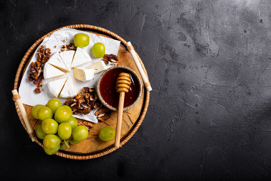 A colorful cheese platter with honey, sweet grapes, and crunchy walnuts, perfect for any gathering or celebration, appetizer for wine, snack board top view
