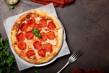 Homemade italian pizza with mozzarella, pepperoni sausages, on a dark background top view copy space for text
