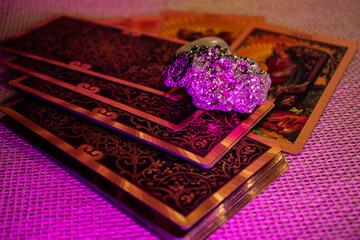 Tarot cards with gold designs of a King and Queen lie on woven fabric. Rock crystal, pyrite, and a...