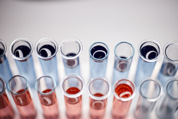Closeup showing multiple glass test tubes filled with various colored liquids arranged in rows on...