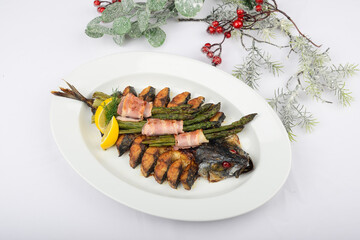 mackerel whole fish baked with asparagus on a white background with New Year's decor