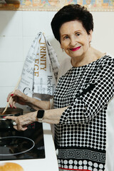 Smiling elderly woman looking at camera while stirring hot chocolate in kitchen