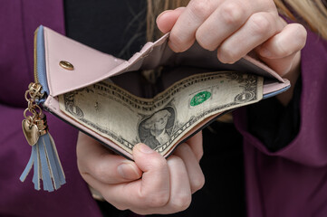 Woman shows empty wallet, only one US dollar inside, poverty