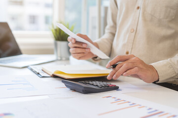 Stressed asian young businessman, employee male using calculator to calculate expenses of monthly,...