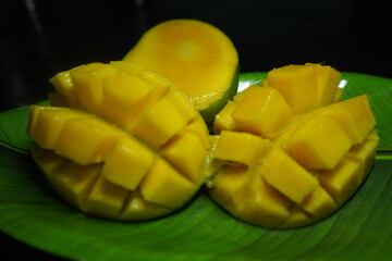 Freshly sliced ripe mango with juicy golden cubes on rustic wooden table, showcasing tropical fruit’s vibrant color and delicious texture.	