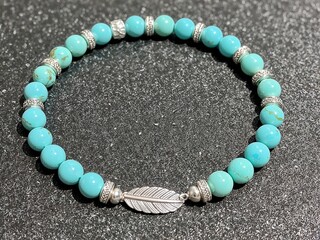 Turquoise beaded bracelet with silver spacers and feather charm centerpiece