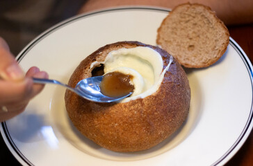 traditional French onion soup with cheese served in a bread bowl in a round plate