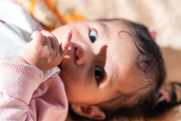 A cute Indonesian baby in warm clothes lying on a colorful blanket. Perfect for themes of...