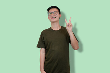 Casual young man making a playful pose with light green background
