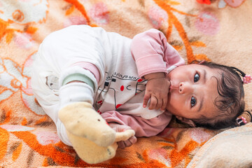 A cute Indonesian baby in warm clothes lying on a colorful blanket. Perfect for themes of...