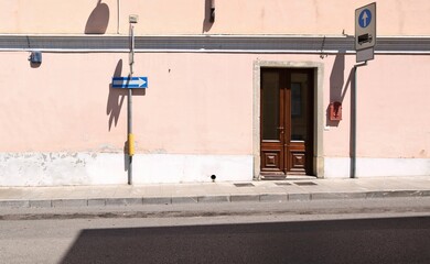 One way sign and no stopping sign at the roadside in an european town. Pink plaster facade,...