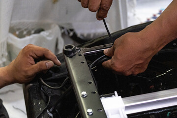 A skilled technician assembling and checking the electrical system and internal mechanism of an automatic electric sofa chair.