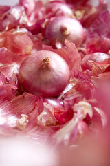 Bulb onions and red onion skins with foreground-style image. Selective focus of food texture in vertical. Concept of abstract red-pink, herb, vegetable, flavor, healthy, organic for background, web.