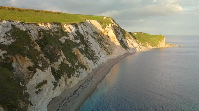 Aerial view of the rugged, chalky cliffs meet the tranquil, azure sea, with a sandy beach nestled at their base, Wareham, England, United Kingdom.