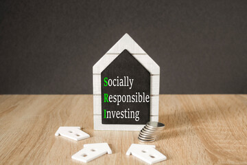 Concept words SRI Socially Responsible Investing on black blackboard. Beautiful wooden table, black...