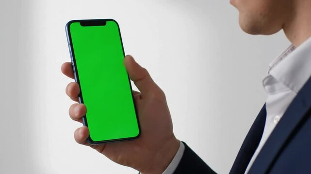 Man in suit holding smartphone with green screen for content insertion and editing