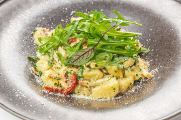 A delicious plate of gnocchi with creamy sauce, sun-dried tomatoes, sauteed mushrooms, parmesan cheese, and fresh arugula on top