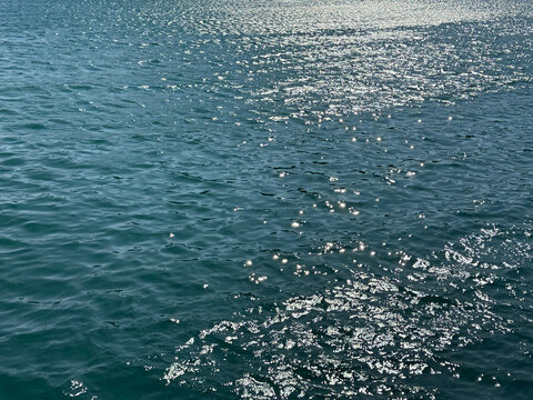 Blue glittering ocean water with sun reflections on surface.