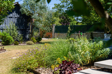 Jardin paysager aménagé par une entreprise spécialisée, avec pelouse, massifs fleuris, arbustes...