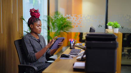 African young adult gen z busy woman lady sitting on chair use tablet device touch screen typing...