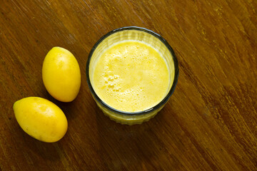 Marian Plum and smoothie placed on wooden table with copy space. Top view two Plum Mango or Thai name Mayongchid. Concept of healthy drink, good food, fiber, fresh fruit, ripe, flavor for print, web.