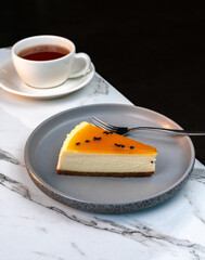 Slice of Lemon Cheesecake on Marble Table with Blurred Tea Cup in Background. Elegant desert scene for cafe menus, pastry ads, and lifestyle content.