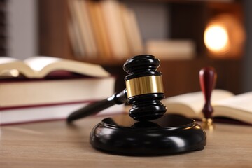 Judge's gavel and books on wooden table indoors, selective focus