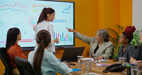 Indian young female old boss lady team leader show chart white board learn study graph data growth serious work place Asian adult girl staff group talk speak share stock trade idea plan job office day