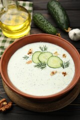 Tasty cucumber soup with dill, walnuts and ingredients on wooden table, closeup